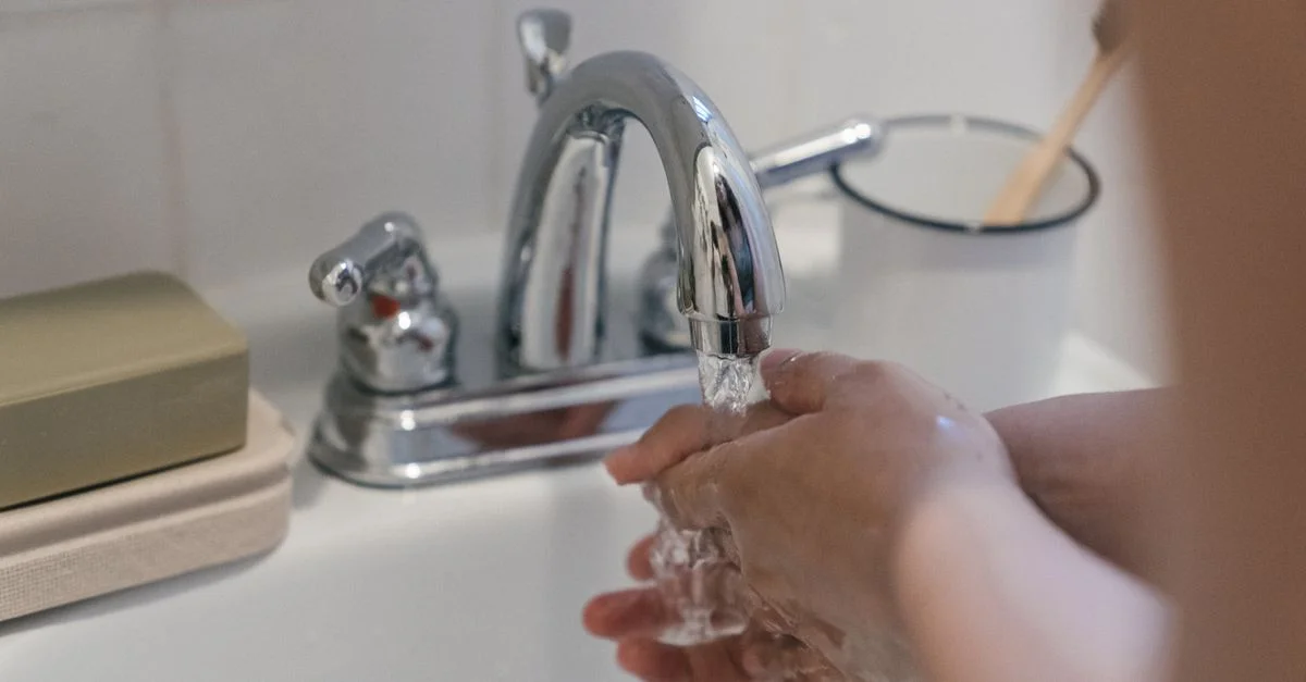 Des mains se lavant sous un robinet avec de l'eau courante, mettant en avant l'hygiène et la propreté.