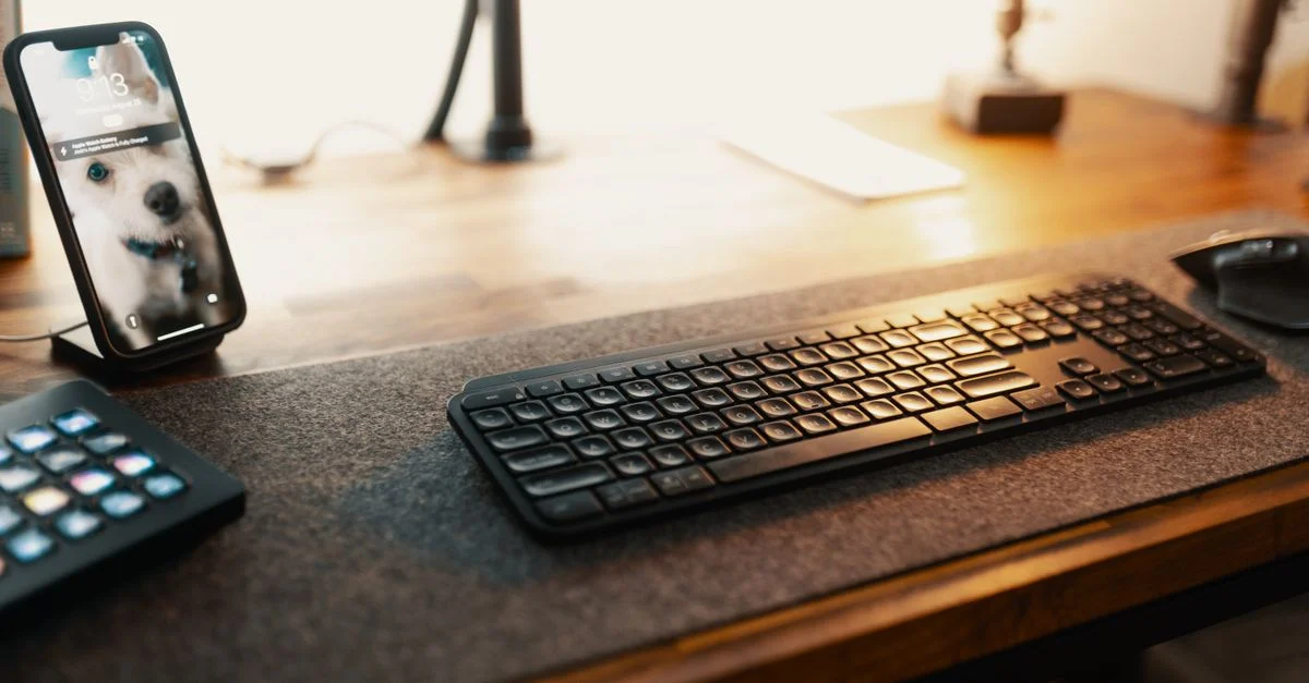 Un bureau bien éclairé avec un smartphone et un clavier, idéal pour des environnements propices à la productivité.
